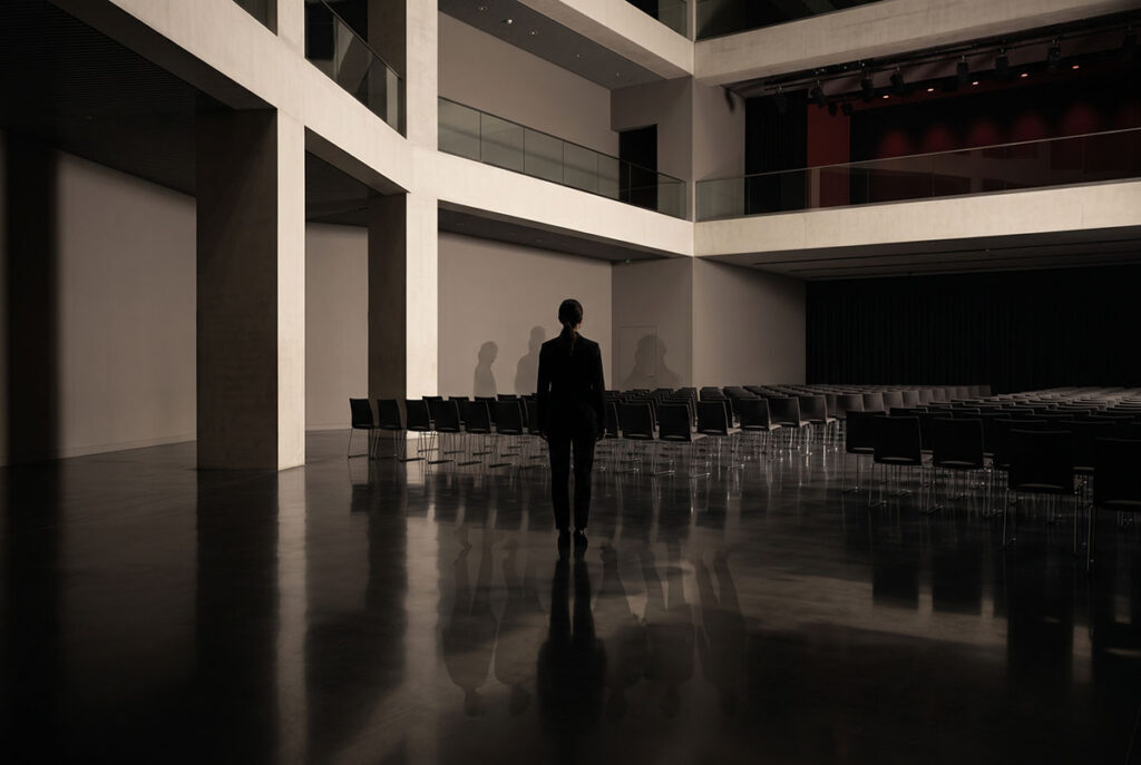A professional stands inside a vast reflective conference space, suggesting identity and belonging within a brand ecosystem.