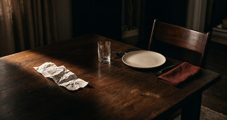 A warm dark dinner table with a crumpled grocery receipt beside an empty place setting, suggesting the difference between observed behavior and direct human intent.